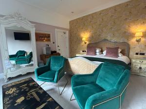 a bedroom with a bed and two chairs and a mirror at Baytree House in Harrogate
