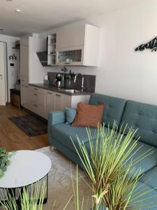 a living room with a blue couch and a kitchen at Apartment Bergzeit Sterzing in Vipiteno