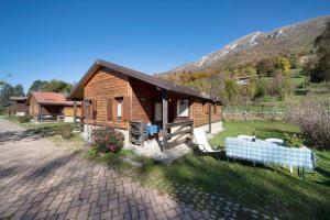 a log cabin in a field next to a mountain at Casa Genziana in Barzio