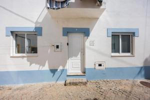 a white and blue building with a door and two windows at Apartamento Carrapateira in Bordeira