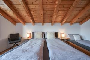 two beds in a room with wooden ceilings and a chair at Ferienwohnung Alpenvogel in Sonthofen