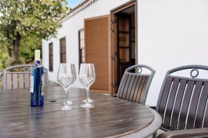 a wooden table with two wine glasses and a blue bottle at Casa El Naranjo Viejo in Tijarafe +23 photos