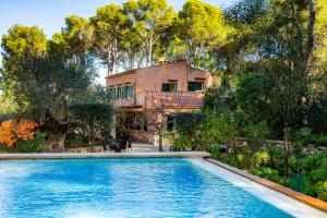 a swimming pool in front of a house with trees at Finca Perello in Felanitx