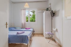 two beds in a room with a window at Stenies Little Nook in Andros