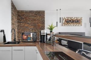 a kitchen with white cabinets and a brick wall at Luxus Appartement mit Panoramablick in Sinsheim +15 photos