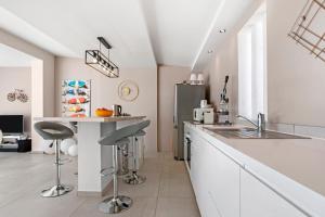 a kitchen with white cabinets and a counter with stools at Villa Artemis piscine Golfe St-Trop in Grimaud