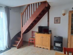 a staircase in a living room with a tv at Duplex Près Du Lac De La Raviège in La Salvetat