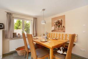 a dining room with a wooden table and a cat laying on the chairs at Ferienhaus Allgäuperle in Altusried