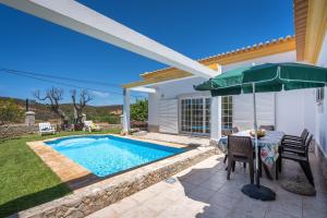 a patio with a pool and a table and an umbrella at Casa Village in Senhora do Verde
