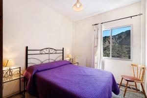 a bedroom with a purple bed and a window at Casa de Berta in Vallehermoso
