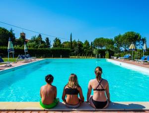 a group of three people sitting in front of a swimming pool at Podere Simonetta - A9 in Cecina +6 photos