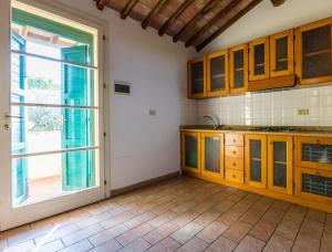a kitchen with wooden cabinets and a large window at Podere Simonetta - A9 in Cecina