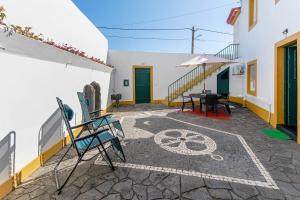 a patio with chairs and a table and an umbrella at Casa do Largo - Acores in Ponta Delgada
