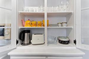 a white cupboard filled with cups and dishes at Casa do Largo - Acores in Ponta Delgada