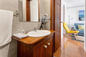 a bathroom with a sink and a yellow chair at Casa do Largo - Acores in Ponta Delgada +17 photos