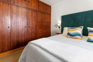 a bedroom with a large white bed with wooden cabinets at Casa do Largo - Acores in Ponta Delgada