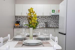 a white dining room table with a vase with yellow flowers at Oásis Fonte Grande in Santo António