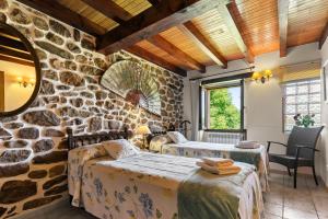 a room with two beds and a stone wall at Casa El Campano in Ontaneda