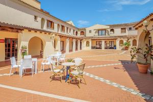 a patio with white chairs and tables in a courtyard at Trilo Piazzetta Garden in San Teodoro