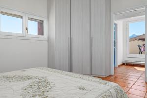 a white bedroom with a bed and two windows at Trilo Piazzetta Garden in San Teodoro