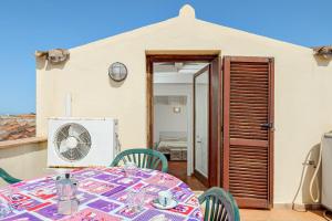a patio with a table and chairs and a fan at Trilo Piazzetta Garden in San Teodoro