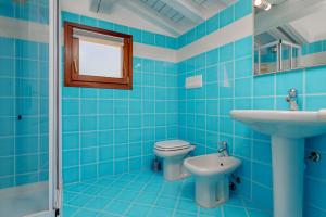 a blue tiled bathroom with a toilet and a sink at Trilo Piazzetta Garden in San Teodoro +12 photos