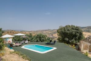 a swimming pool in a yard with chairs and umbrellas at Finca El Porvenir in El Gastor