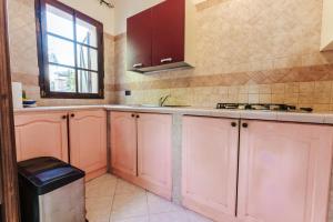 a kitchen with pink cabinets and a window at Casa Vacanze Villa Carola in Quartu SantʼElena