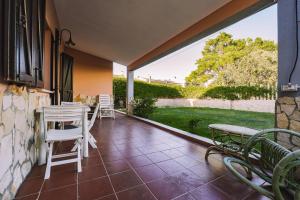 a patio with chairs and tables and a view of a yard at Casa Vacanze Villa Carola in Quartu SantʼElena