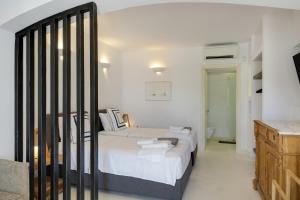 a white bedroom with two beds and a bathroom at Blueros - Grey Suite in Megas Gialos - Nites +18 photos