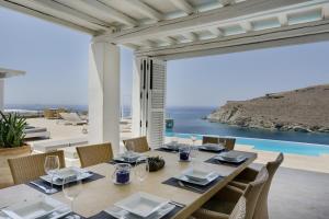 a dining table with chairs and a view of the ocean at Blueros - Grey Suite in Megas Gialos - Nites