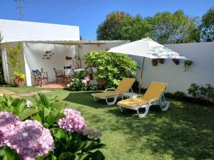 a yard with chairs and an umbrella and flowers at Casa da Ria 78 - Family House in Torreira