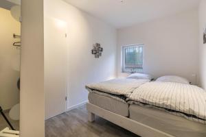 a white bedroom with a bed and a window at Ferienhaus Ostseeblick in Munkbrarup