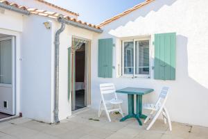 a table and chairs on a patio with a house at Chambres d’hôtes Chantal Hereaudeau in Ars-en-Ré