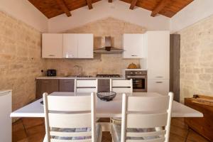 a kitchen with white cabinets and a table and chairs at Il Flauto Magico in Modica +16 photos