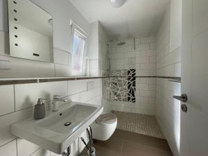 a white bathroom with a sink and a toilet at Ferienhaus Specht in Zossen +37 photos
