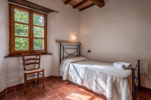 a bedroom with a bed and a chair and a window at Ginestra in Arcidosso