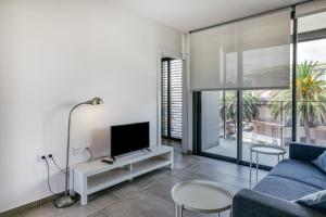 a living room with a blue couch and a tv at Rostella Apartment in Roses