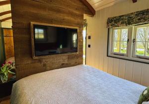 a bedroom with a bed and a flat screen tv at Melbury Hut in Shaftesbury
