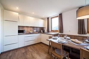 a kitchen with white cabinets and a table with chairs at Flatschhof - Chalet Flatsch in Kastelbell-Tschars