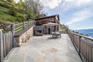 a stone patio with an outdoor fireplace in front of a log cabin at Flatschhof - Chalet Flatsch in Kastelbell-Tschars