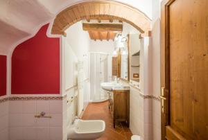 a bathroom with a white sink and a red wall at L'arco della Fonte in Gaiole in Chianti +14 photos