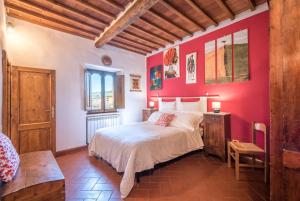 a bedroom with a bed and a red wall at L'arco della Fonte in Gaiole in Chianti