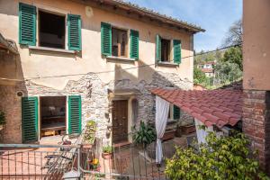 a house with green shuttered windows and a balcony at L'arco della Fonte in Gaiole in Chianti