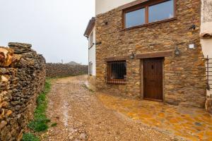 a stone house with a door and a stone wall at Masía Parreta Estancia El Refugio in Villafranca del Cid