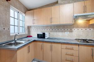 a kitchen with wooden cabinets and a sink and a microwave at Casa Marrero in La Guancha