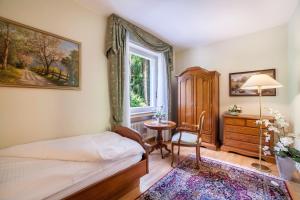 a bedroom with a bed and a window and a table at Villa Coris Ferienwohnung Magnolia in Merano