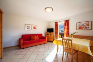 a living room with a red couch and a table at Gasserhof Ferienwohnung Edelrot in Caines
