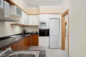 a kitchen with a white refrigerator and a sink at Cosy Two Bedroom Apartment in Cabaços
