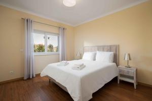 a bedroom with a large white bed with a window at Cosy Two Bedroom Apartment in Cabaços +7 photos